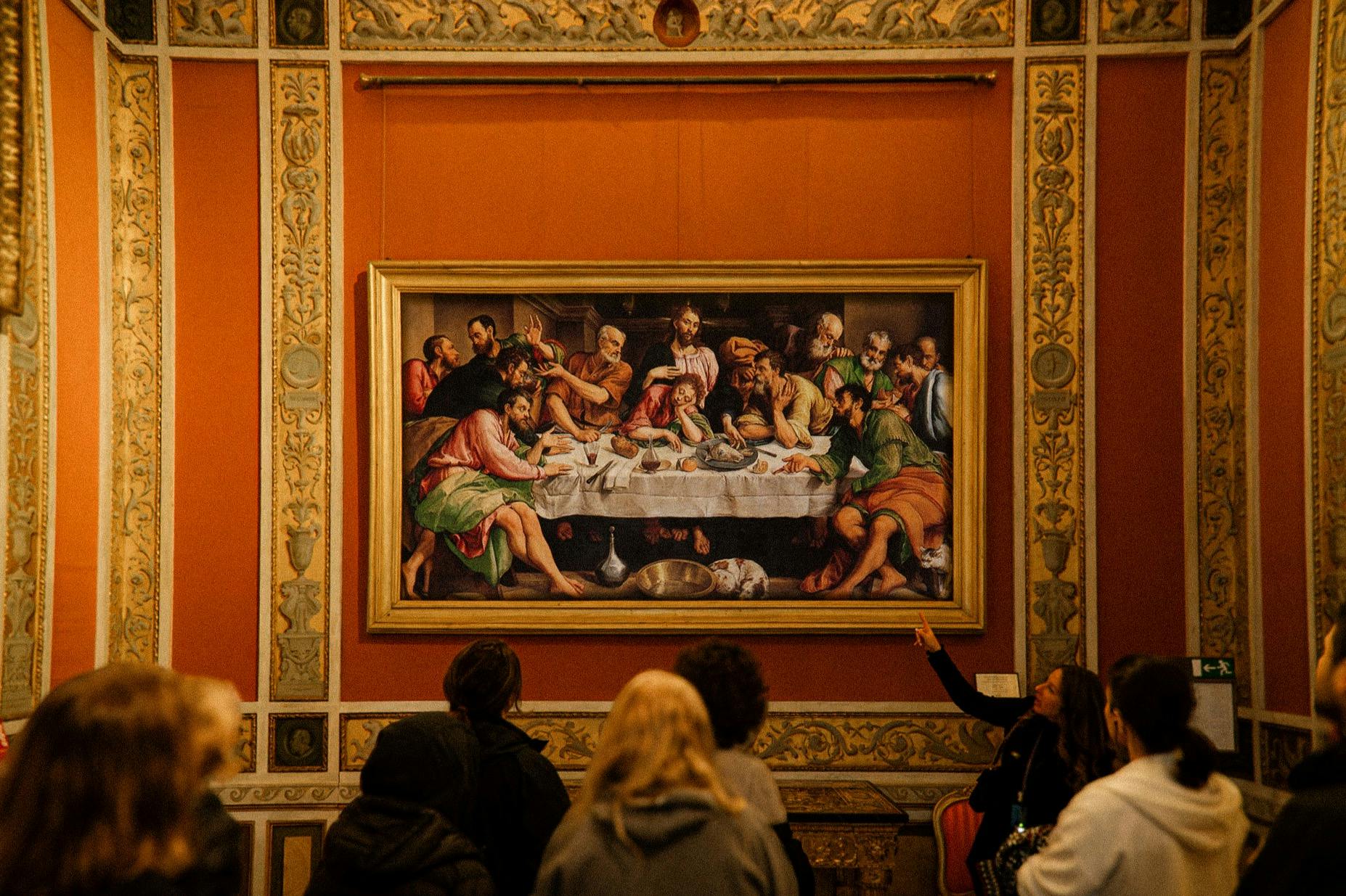 博物馆里的人们正在观看一幅描绘历史宴会场景的大型框架画。