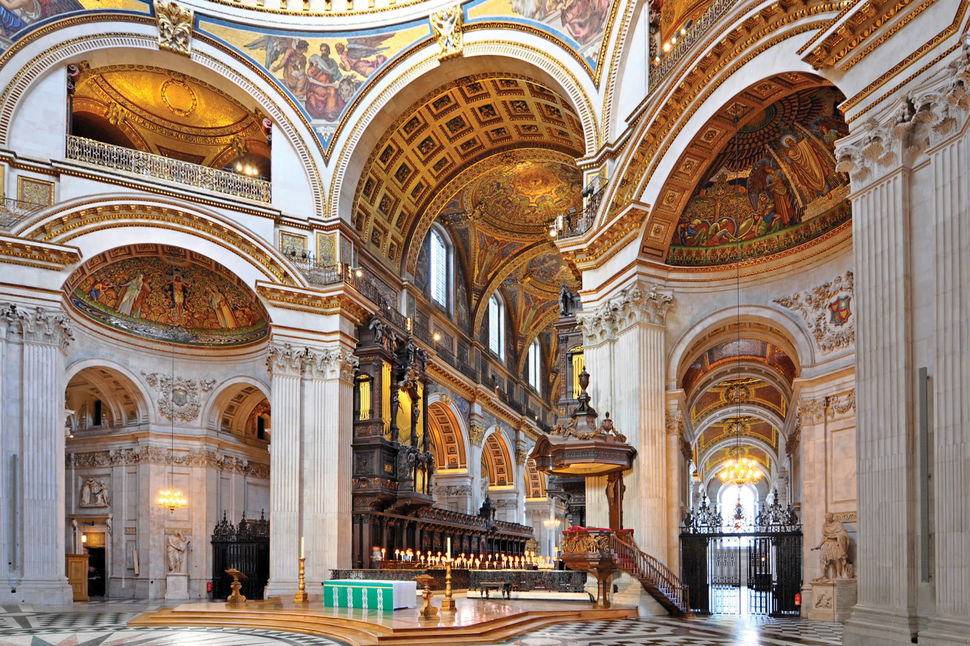 Interior of a grand cathedral with ornate arches, detailed frescoes, and a central altar with lit candles.