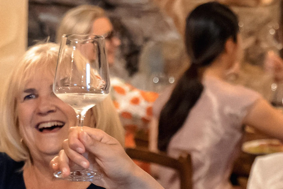 A group of people enjoying a meal and raising glasses in a celebratory toast in a cozy restaurant setting.