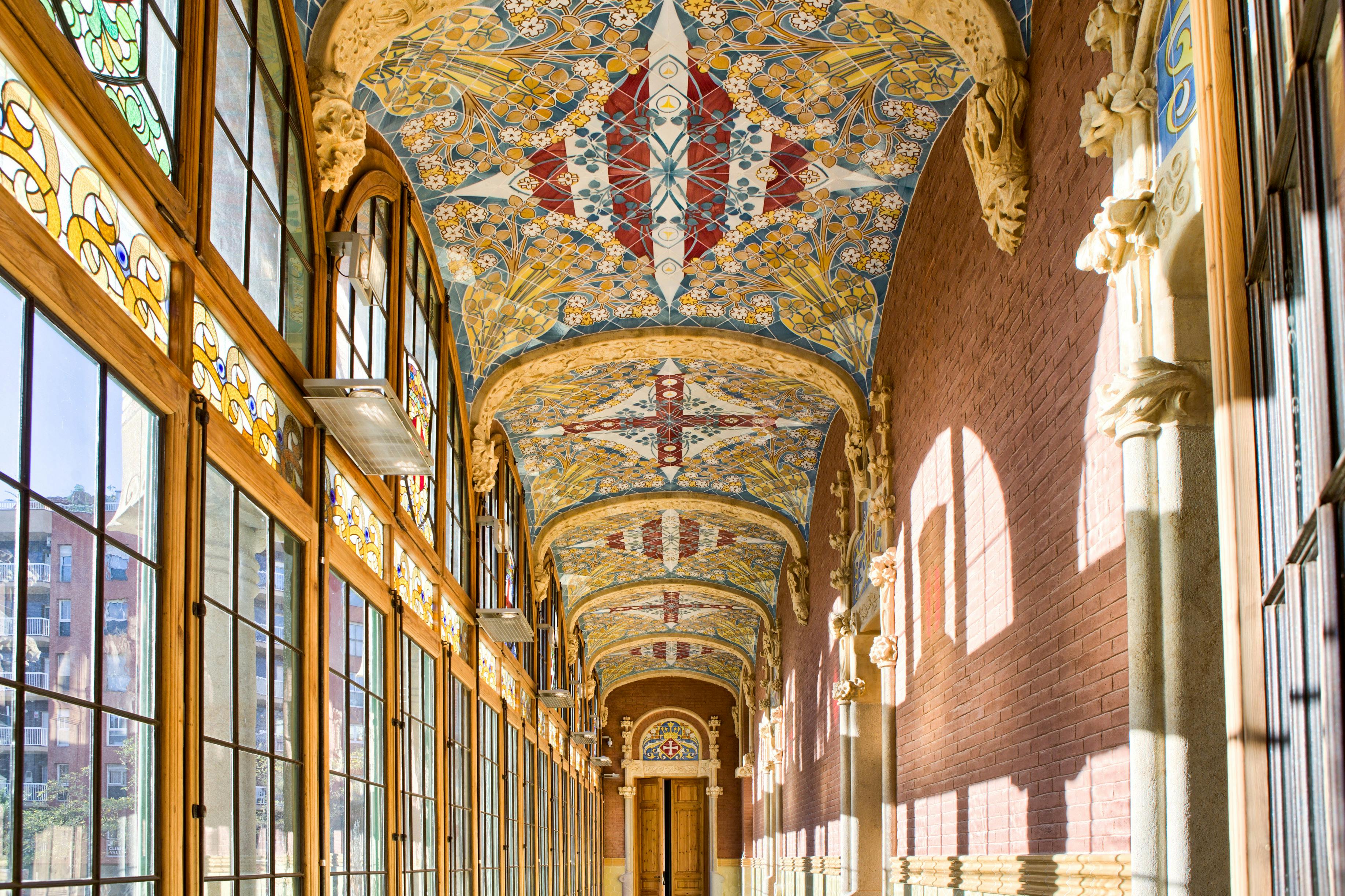 Couloir orné de vitraux colorés et d'un plafond voûté richement décoré de motifs complexes.