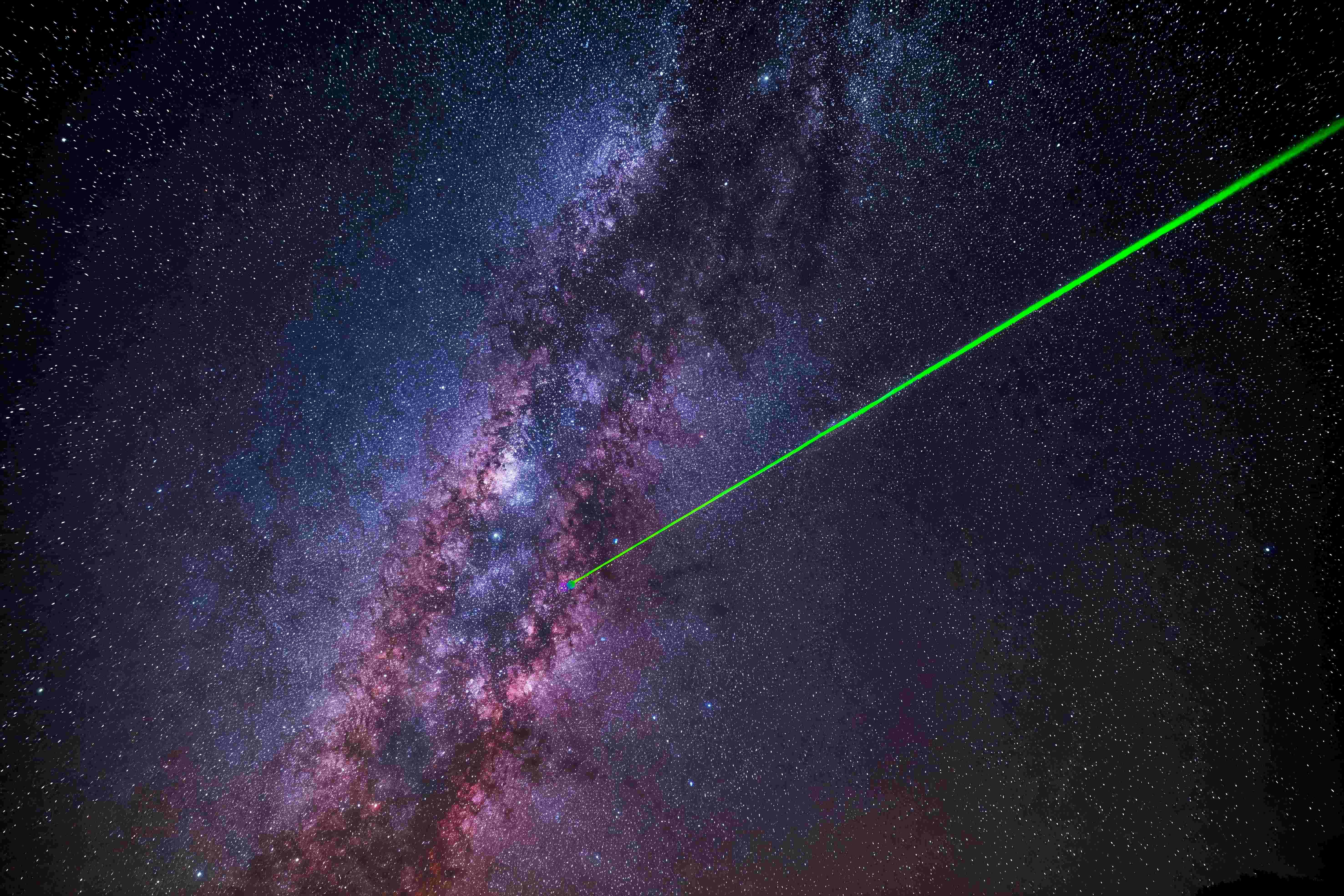 緑色のレーザー光線が、夜空にある鮮やかな星で満たされた天の川銀河を照らしています。