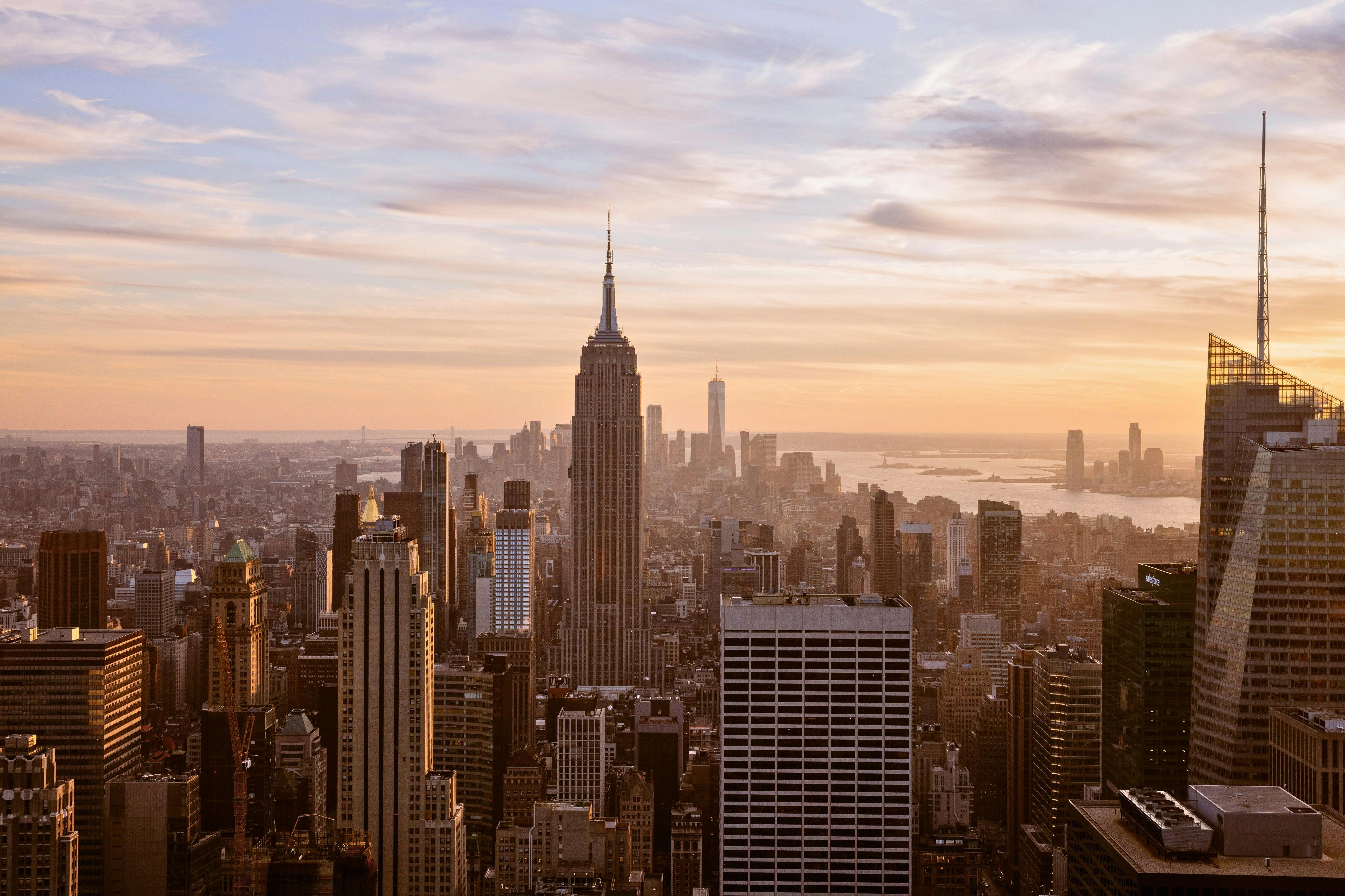 Vue d'un paysage urbain où l'Empire State Building occupe une place centrale au coucher du soleil.