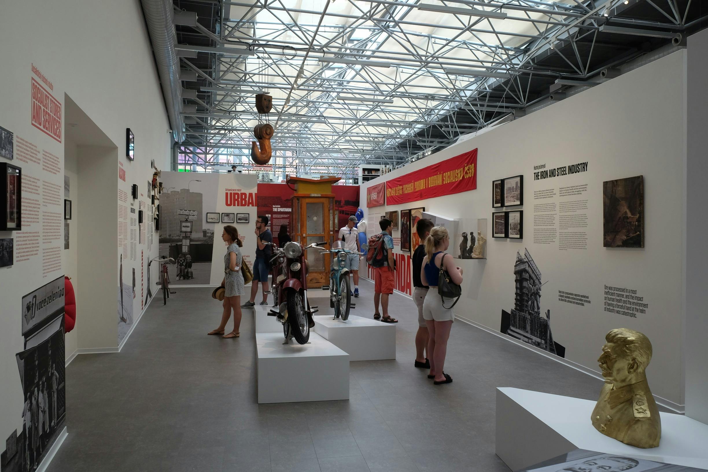 探索城市主题博物馆的人们，这里有老式摩托车、信息展示和工业主题装饰品。
