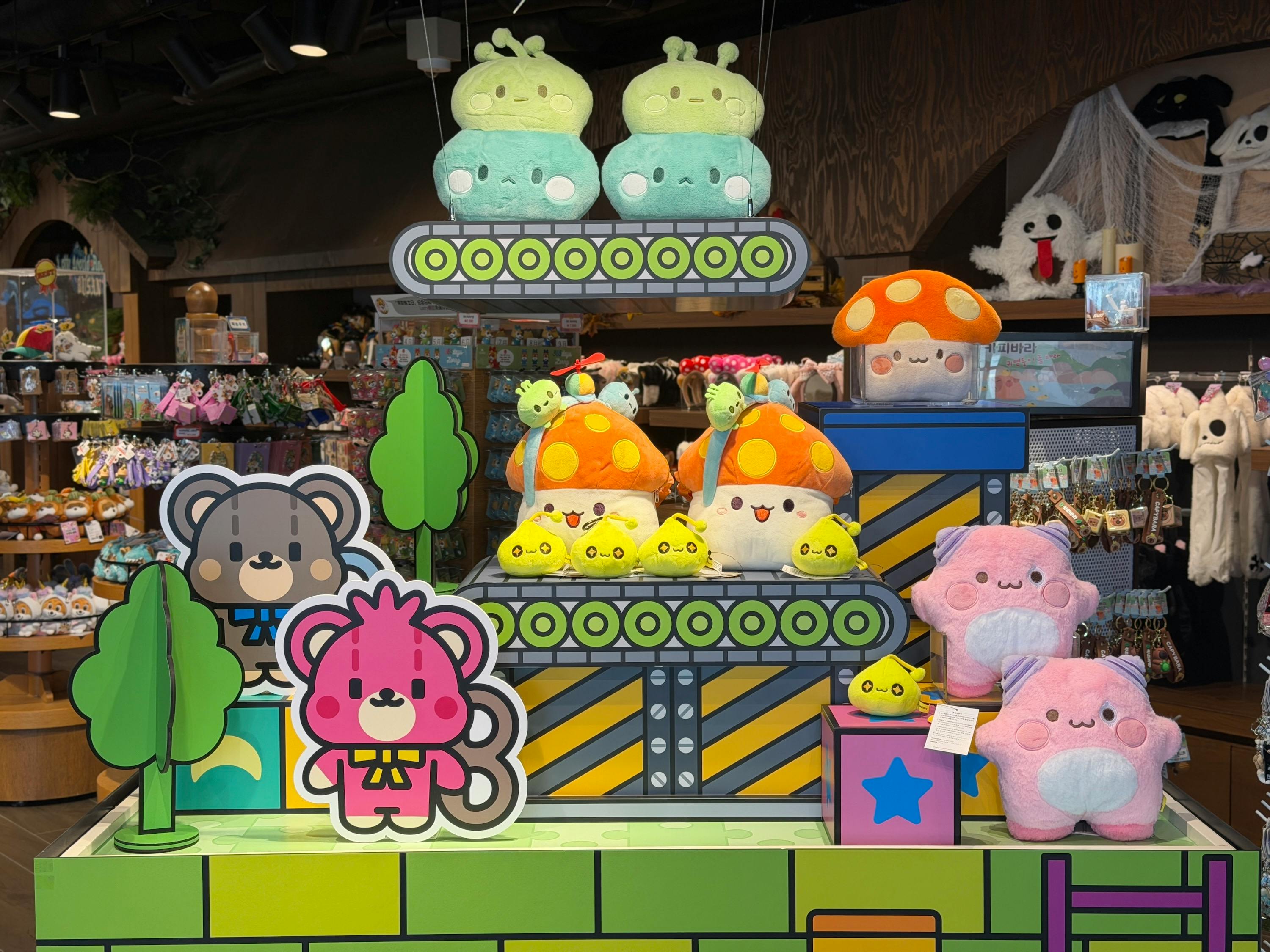 A display of colorful plush toys, including mushrooms, animals, and trees, arranged on a decorative shelf in a store.