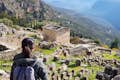 Gäste machen ein Foto mit der archäologischen Stätte von Delphi im Hintergrund