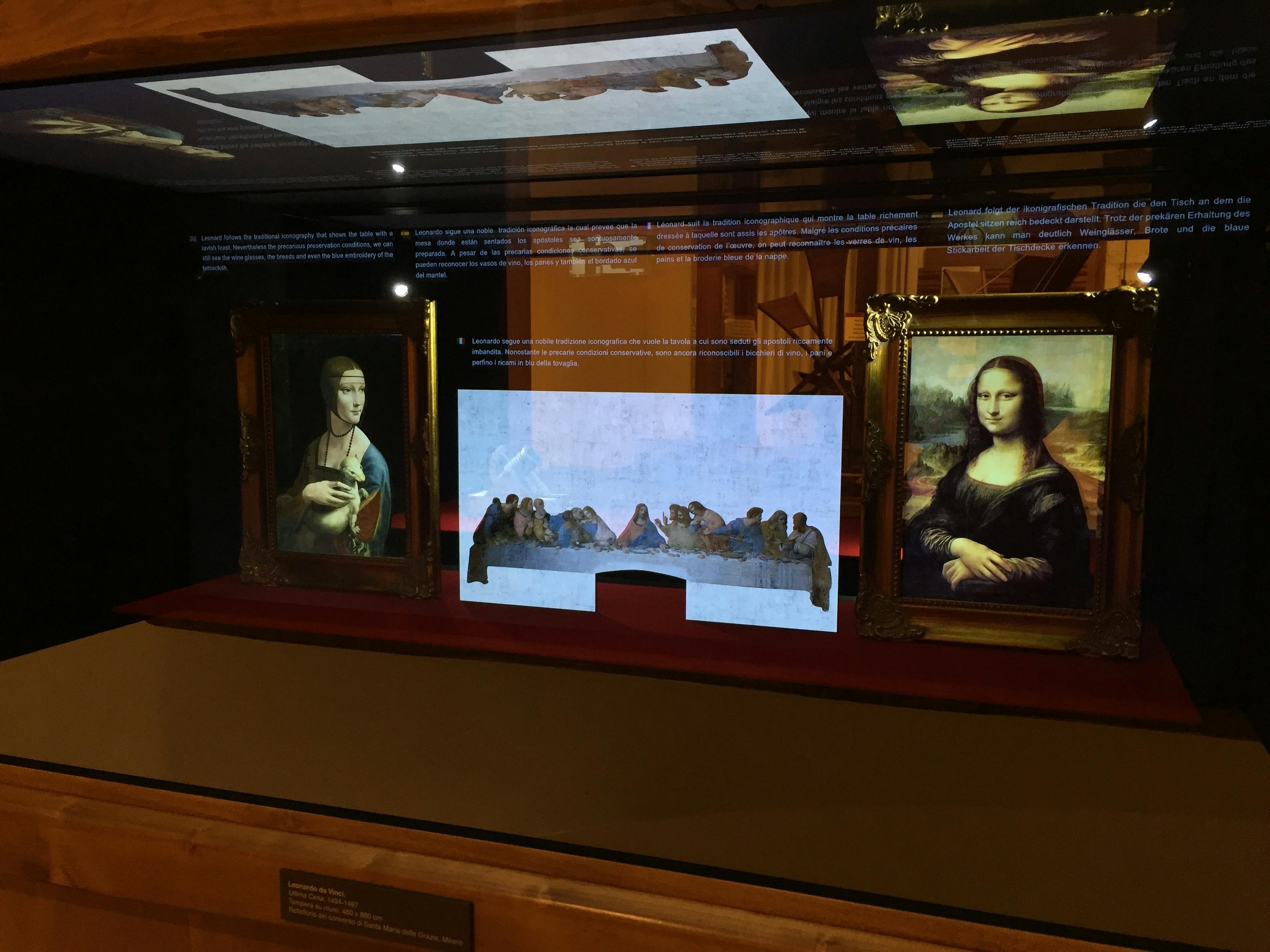 Display case with framed paintings, including the Mona Lisa and The Last Supper, under soft lighting.
