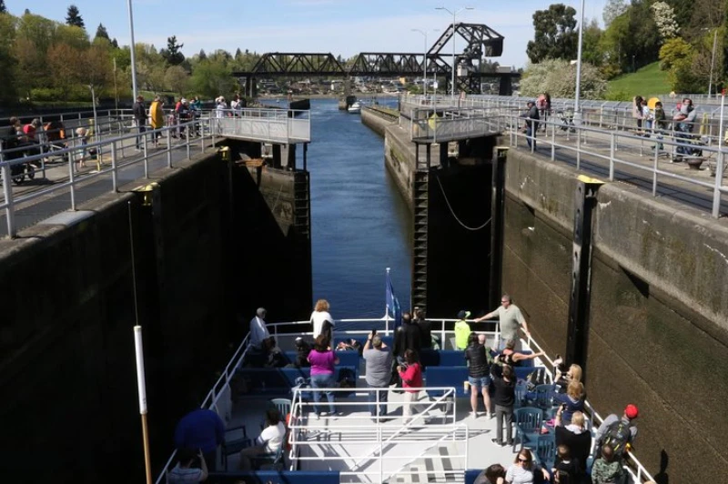 People are on the outer deck of an Argosy boat taking photos as doors of the locking chamber close behind the boat