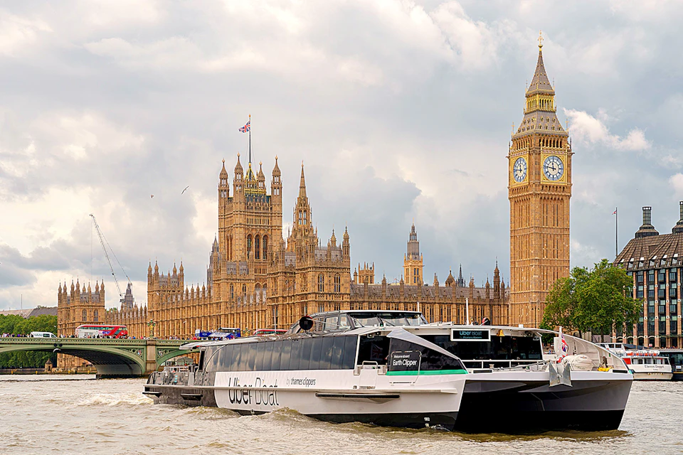 A riverboat labeled 'Uber Boat' on the Thames with the Palace of Westminster and Big Ben in the background.