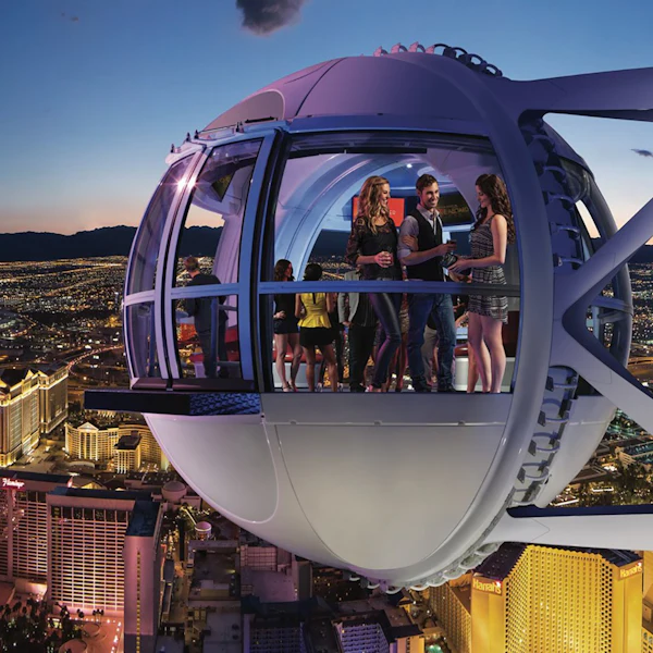 Gruppo di persone che si godono la vista in una capsula della ruota panoramica High Roller, con vista sul paesaggio urbano illuminato di Las Vegas al tramonto.