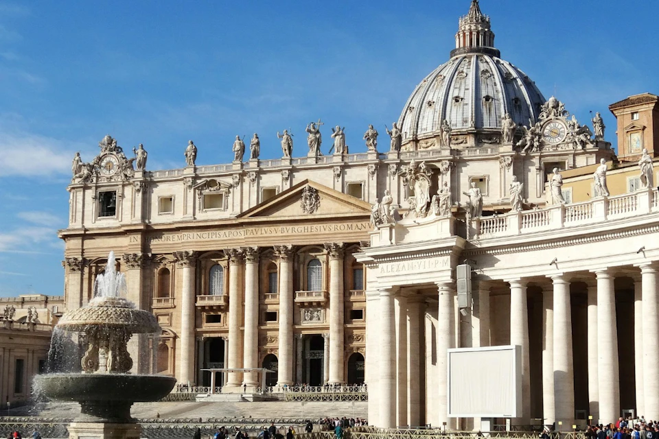 A view of St. Peter's Basilica in Vatican City, showing its ornate architecture and dome under a clear blue sky.