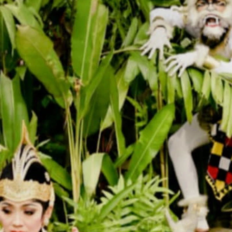 Two performers in traditional costumes enact a dance in a lush garden with a statue of a monkey in the background.