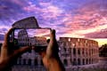Um turista tira uma foto do Coliseu com seu telefone celular.