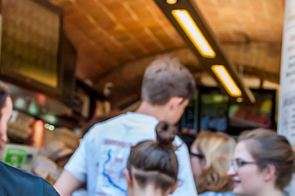 An expressive man in an apron stands in front of Gelateria Dondoli, with a crowd gathered near the entrance.