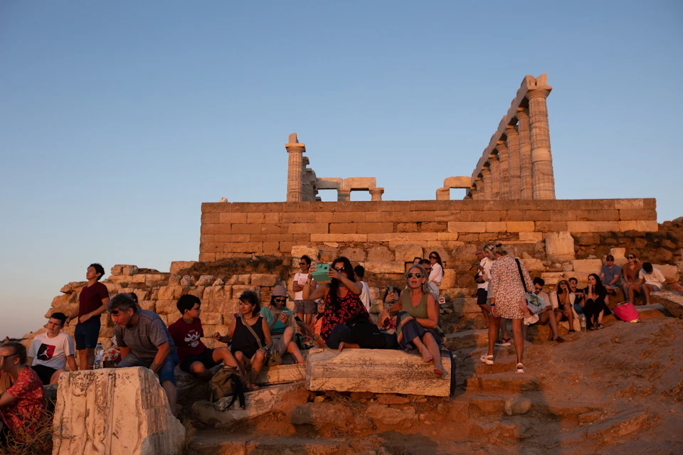 Crowds gather at the Temple of Poseidon in Cape Sounion to enjoy the golden hour and capture the perfect sunset shot.