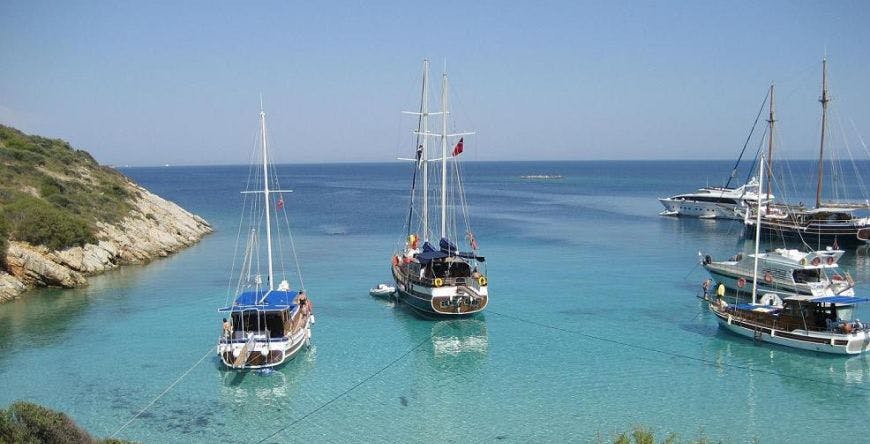 고요한 바다와 푸른 하늘을 배경으로 청록색의 맑은 물에 정박한 두 척의 요트.