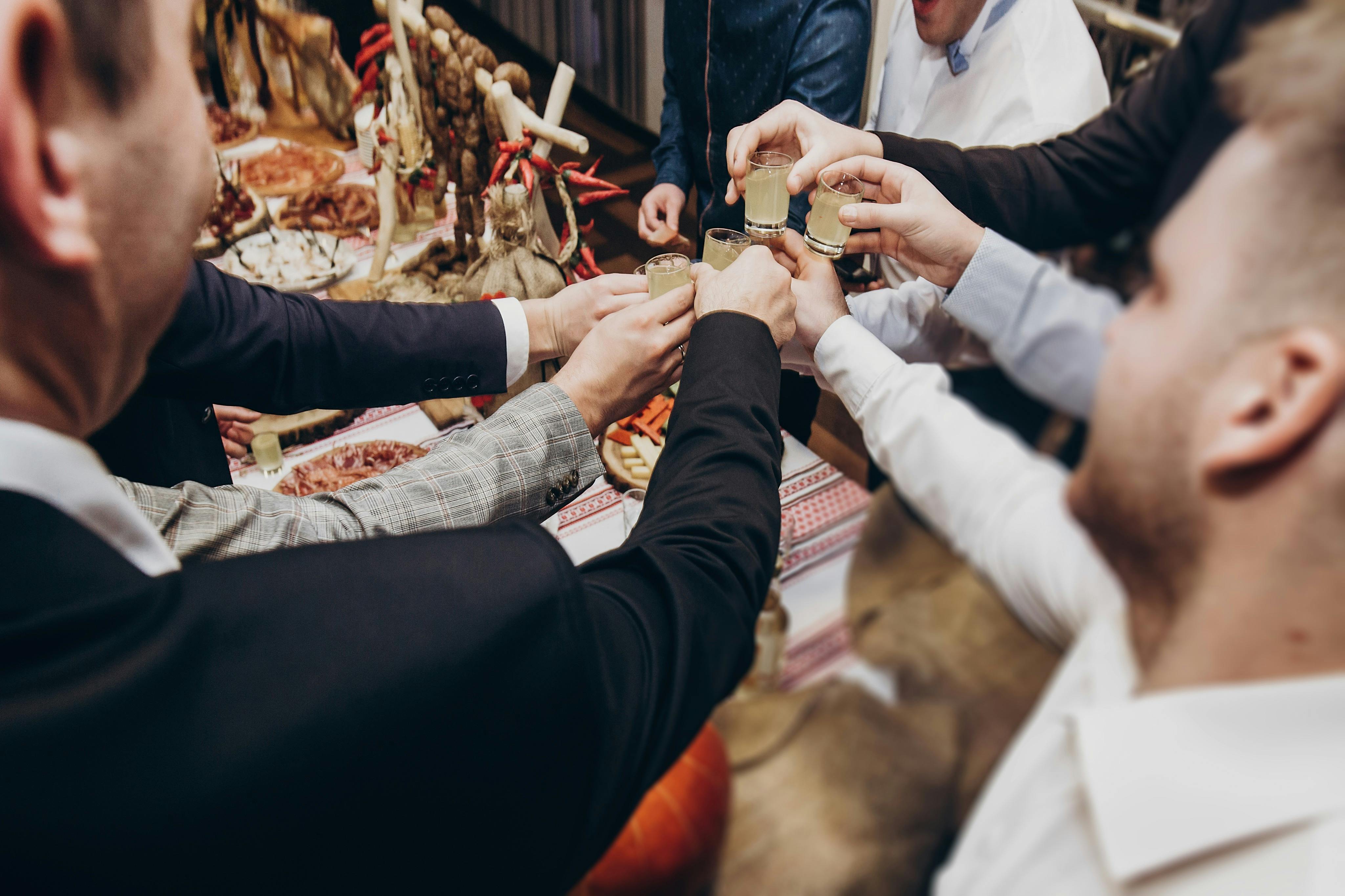 Un groupe de personnes portant un toast avec de petits verres autour d'une table avec de la nourriture et des décorations.