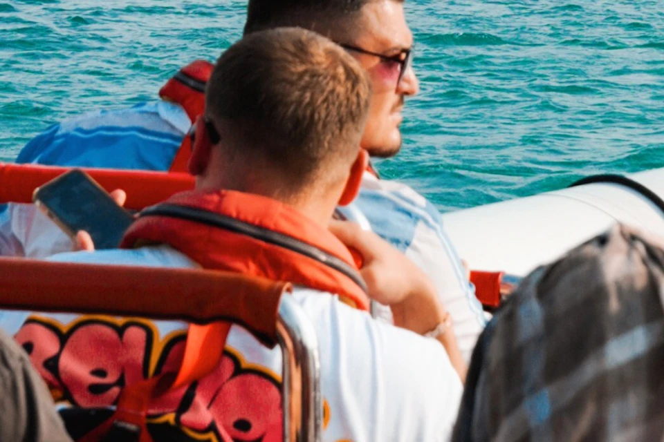 Group of people wearing life jackets on a boat with a city skyline featuring tall buildings in the background.