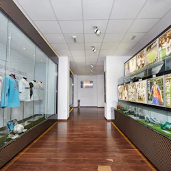 En museigång som visar inramade fotografier och sportminnesmärken, inklusive tröjor och fotbollar, längs glasfodral.