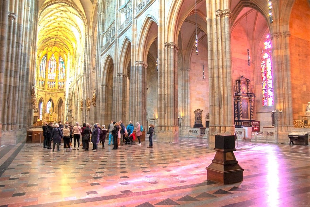 A group of people inside a large cathedral with tall arches and colorful stained glass windows.