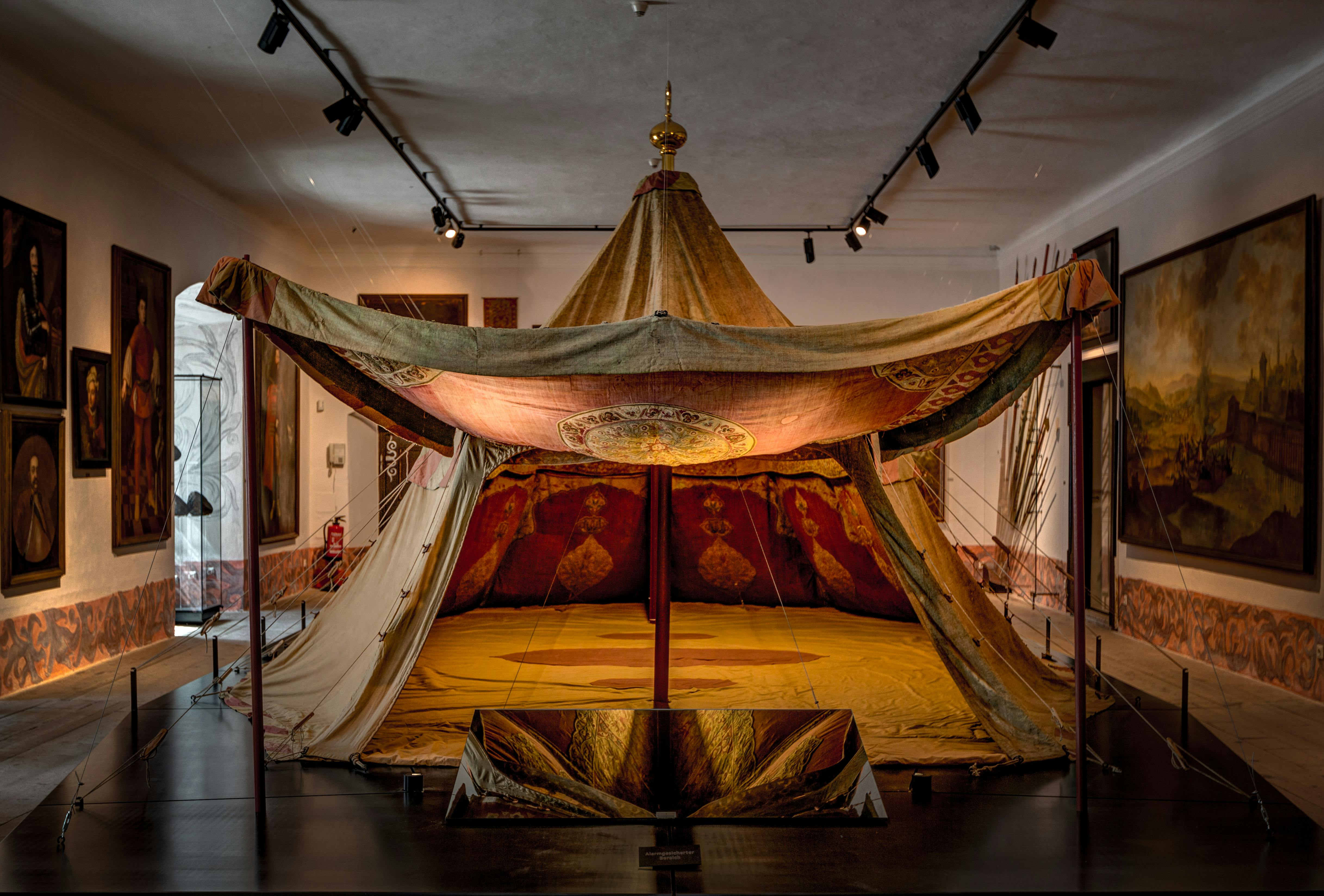 부드러운 조명으로 꾸며진 박물관 방에 장식 무늬가 있는 역사적인 화려한 텐트입니다.