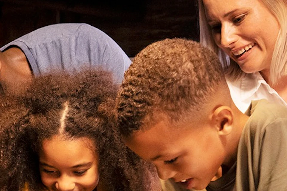 Two adults and two children touch sea creatures in a tide pool exhibit at an aquarium.