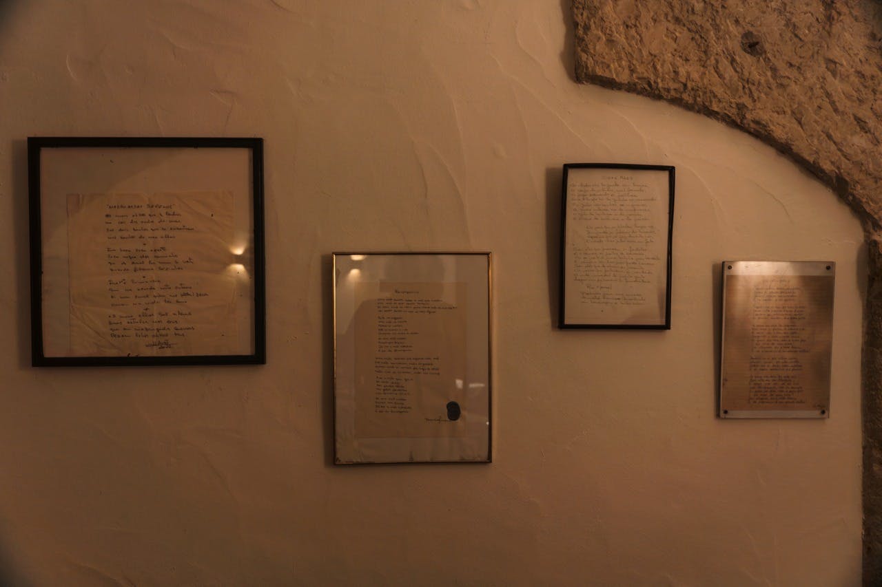 Na béžové texturované stěně s kamenným přízvukem jsou vystaveny tři zarámované ručně psané dokumenty.