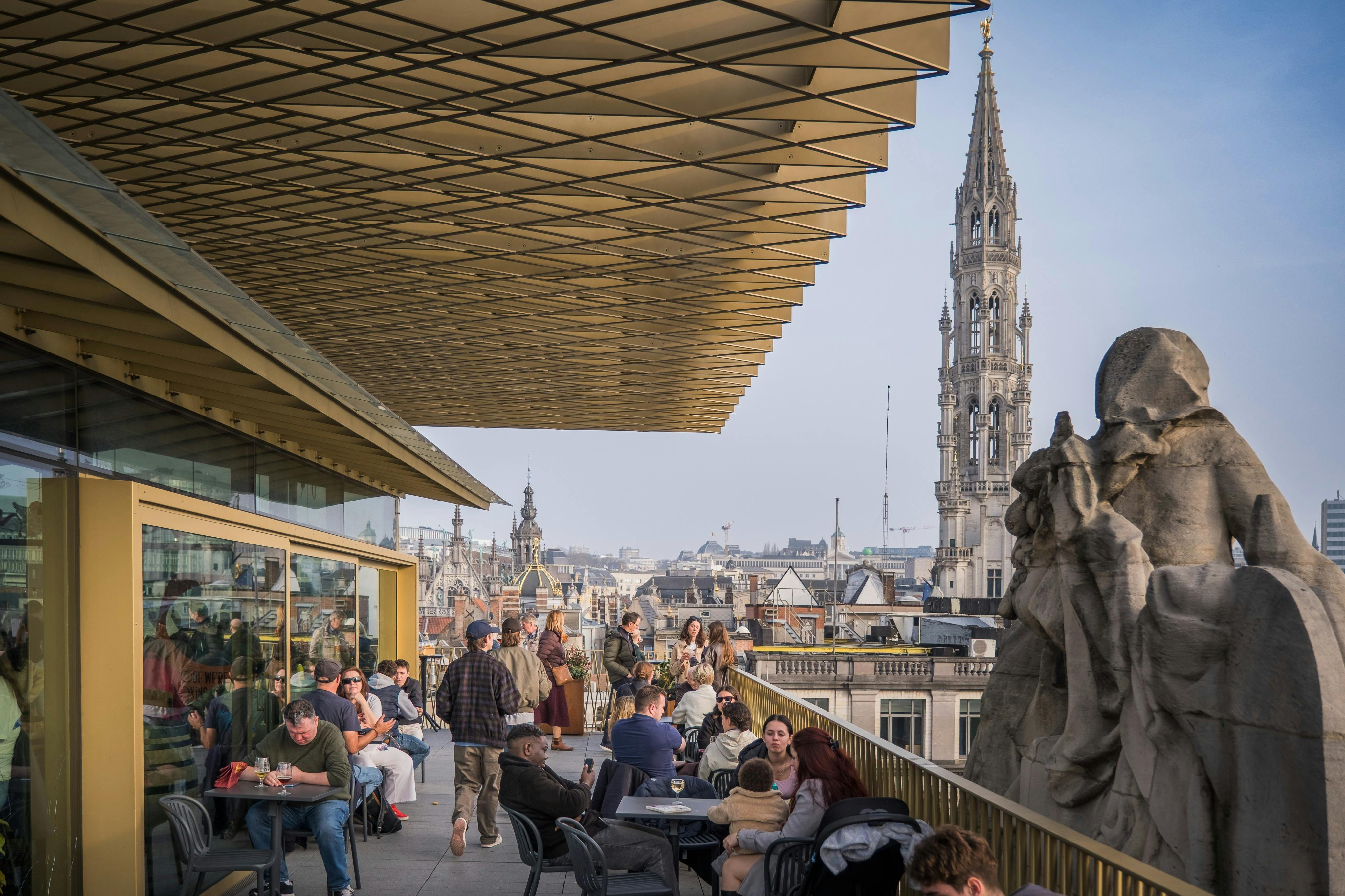 人们坐站在屋顶露台上，背景是城市景观和高大华丽的塔楼。