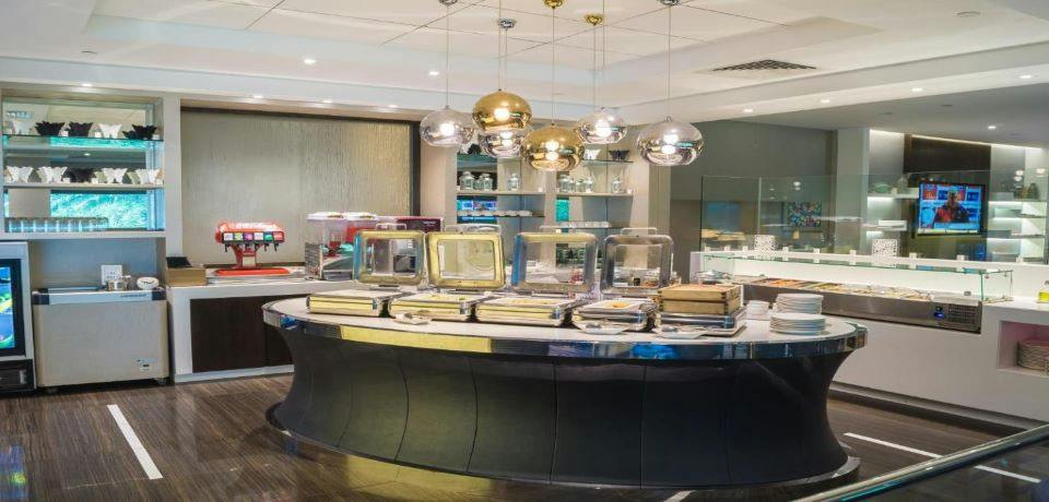 Buffet station with covered dishes and metallic pendant lights in a modern dining area.