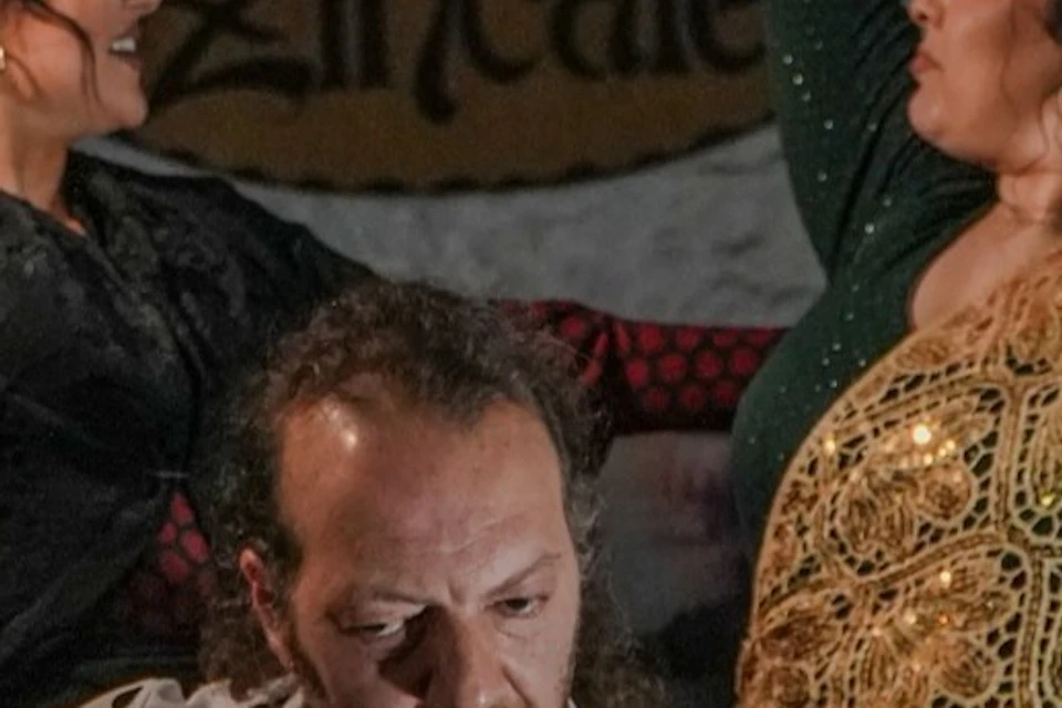 A guitarist plays whilst two dancers perform with dramatic hand movements in a room with a sign reading ‘Zincale’.