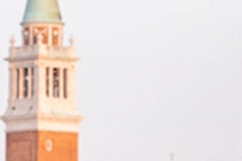 A tour guide speaks to a group in front of the Palazzo Ducale in Venice, with a church tower visible in the background.