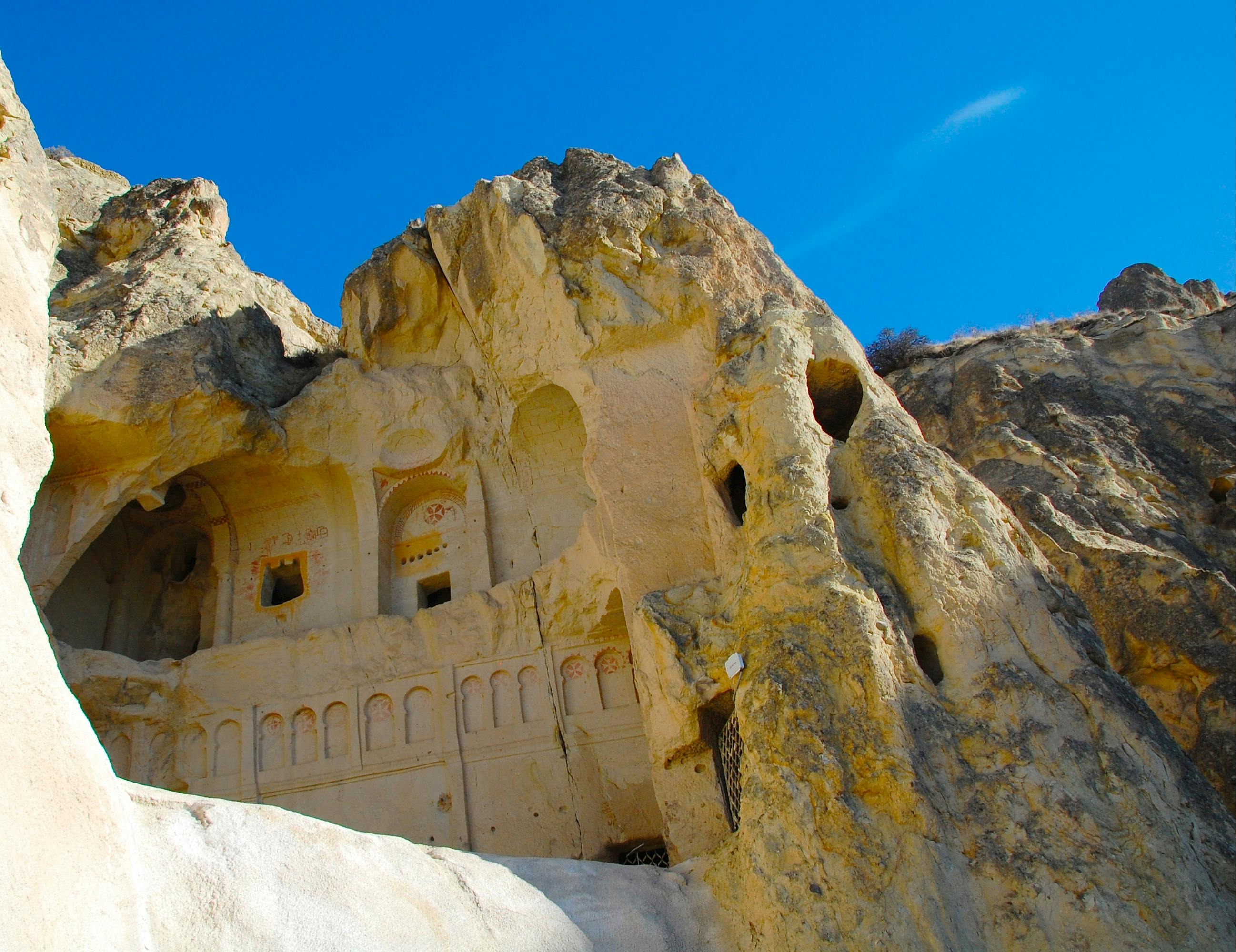 古老的岩石切割建筑在晴朗的蓝天下雕刻成岩石悬崖。
