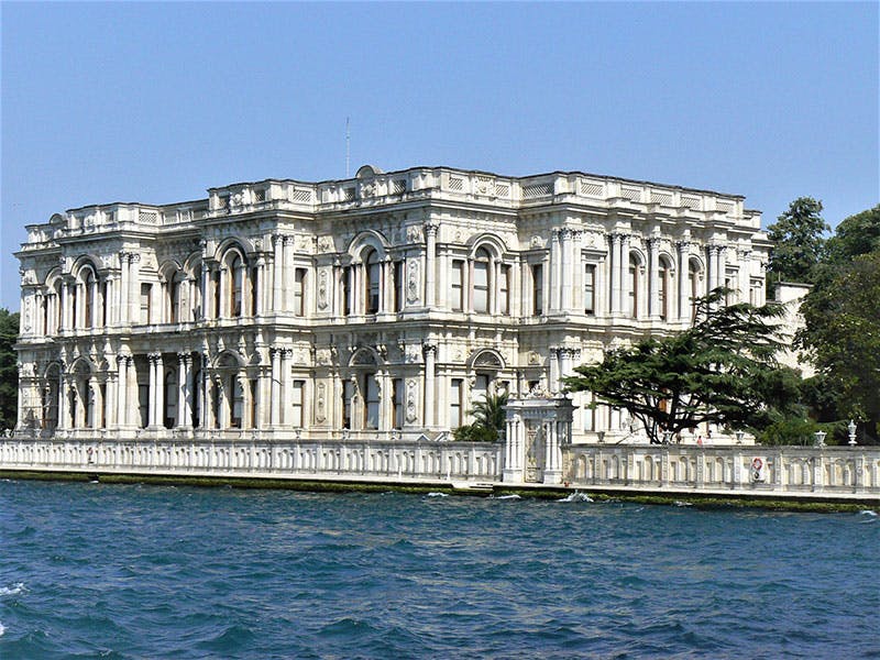 Edificio ornato in stile neoclassico con finestre ad arco e dettagli intricati, situato sul lungomare.