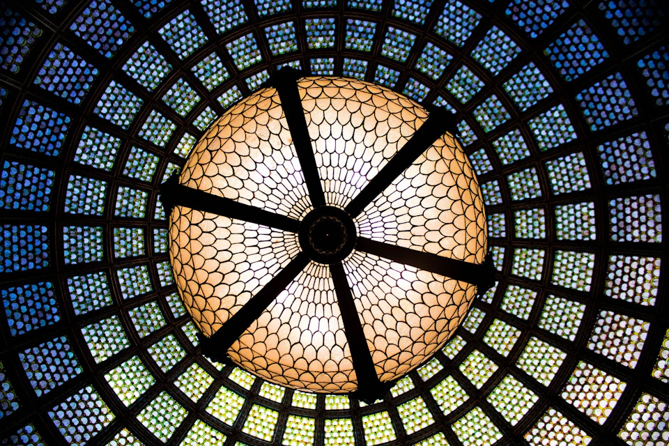 Intricately patterned dome with stained glass, featuring a large central light fixture with dark metal supports.
