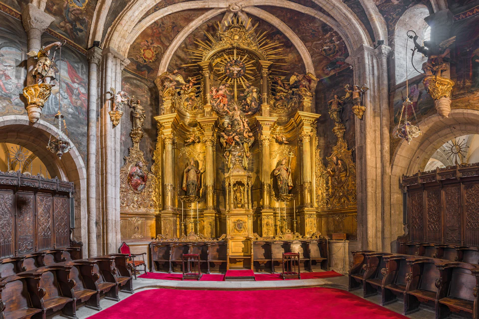 A richly decorated church altar with golden details, statues, and red carpet in front, surrounded by ornate architecture.