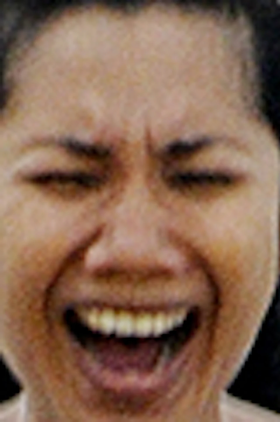 Person laughing joyfully on a log ride styled like a cartoonish shark as water splashes around.