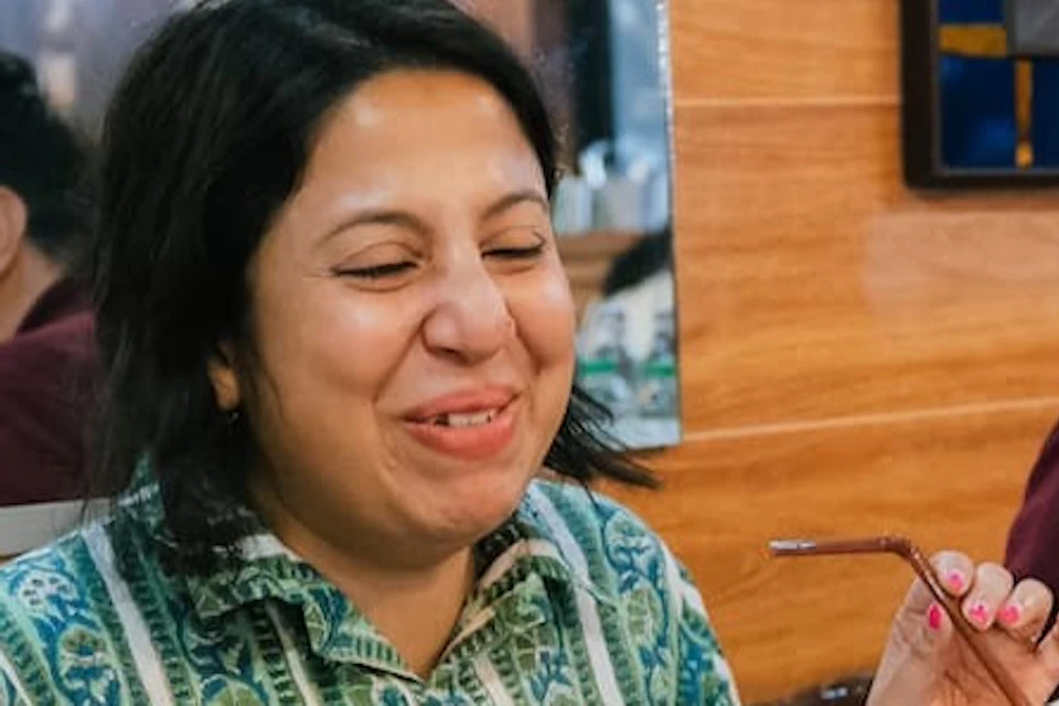 Three people sitting at a table in a restaurant, smiling and enjoying a meal with various dishes in front of them.