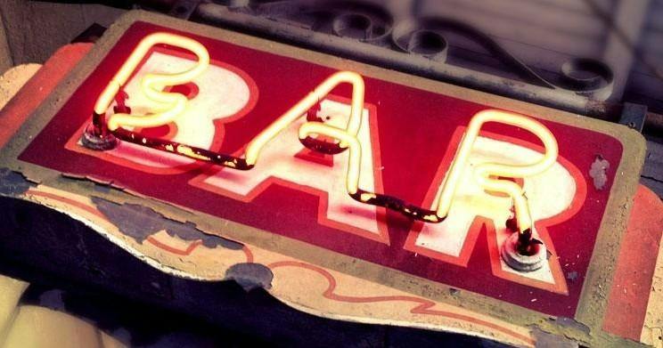 A red and white neon sign displaying the word "Bar," with visible wear on the edges of the sign.