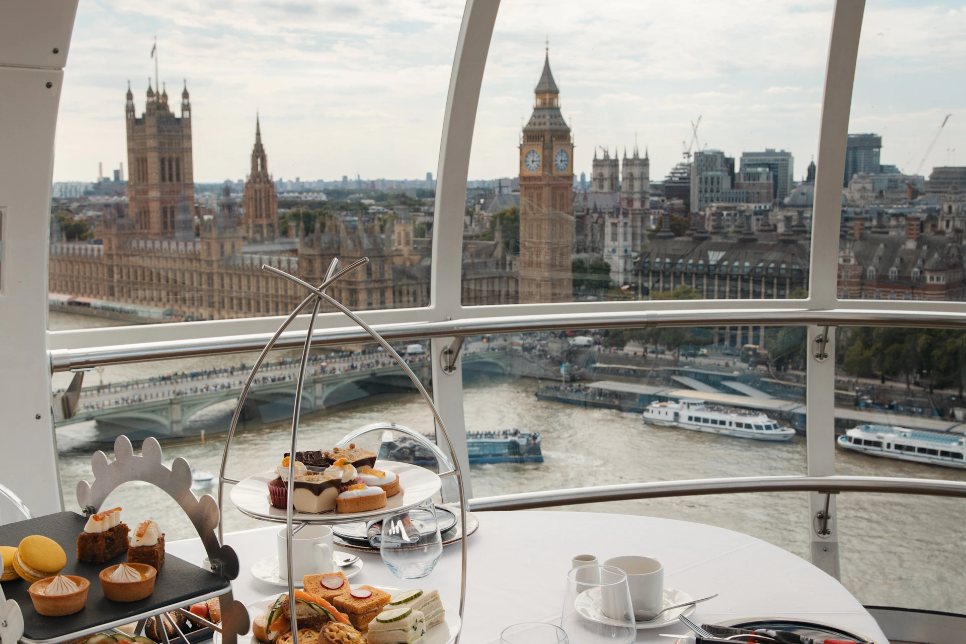 Afternoon tea setup within the London Eye capsule overlooking Big Ben, the Thames River, and the Houses of Parliament.