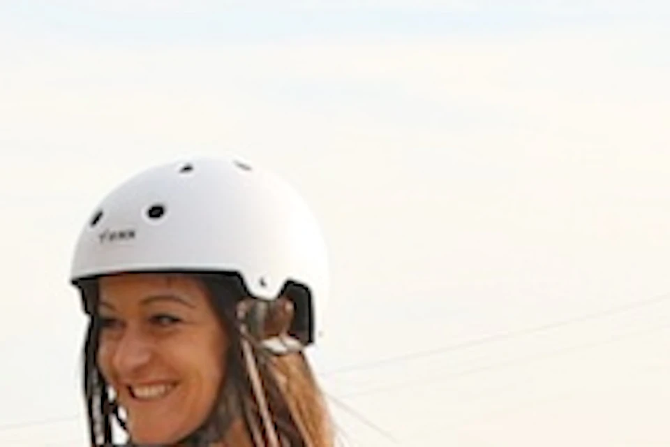 Four people wearing helmets ride Segways on a paved area with a cityscape and a tower in the background.