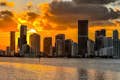 The golden night sky hugs Miami's skyline, casting a bright reflection on the calm waters.