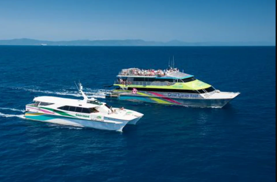 Two colorful tour boats with passengers are sailing on a calm blue sea under a clear sky.