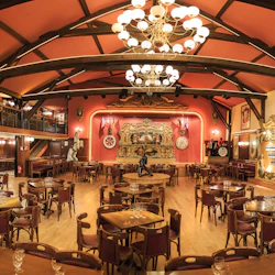 En rymlig, utsmyckad restaurang med träbord, röda stolar, ljuskronor och en genomarbetad scen med ett musikaliskt tema.