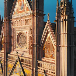 Facade of a gothic cathedral with ornate decorations, stained glass windows, and detailed mosaics depicting religious scenes.