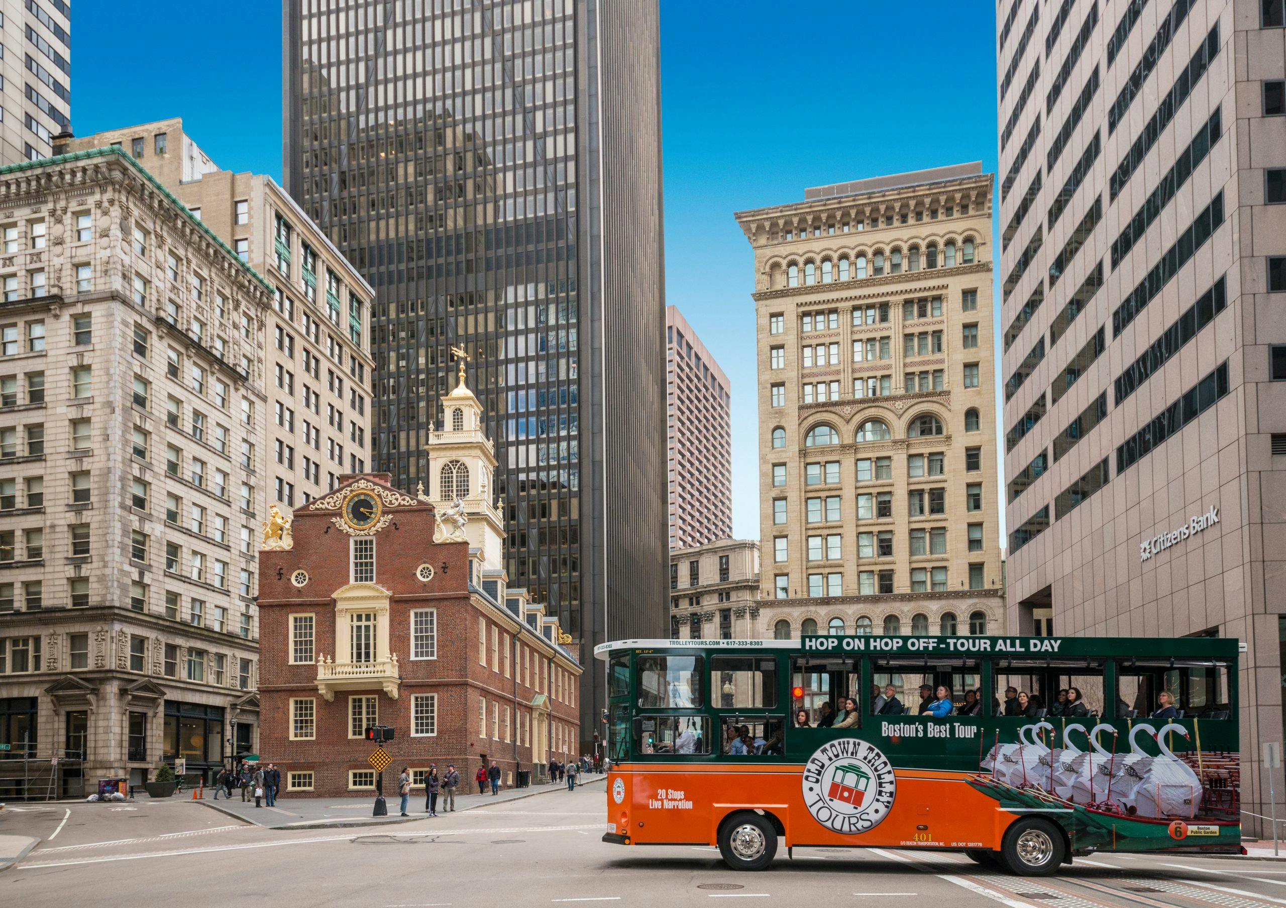 Downtown Boston met historische en moderne gebouwen en een oranje en groene tourbus met het opschrift "Boston's Best Tours".
