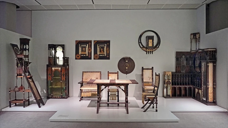 Room with an antique wooden dining set, including a table, chairs, and a bench. Two framed artworks and circular wall decor are visible.