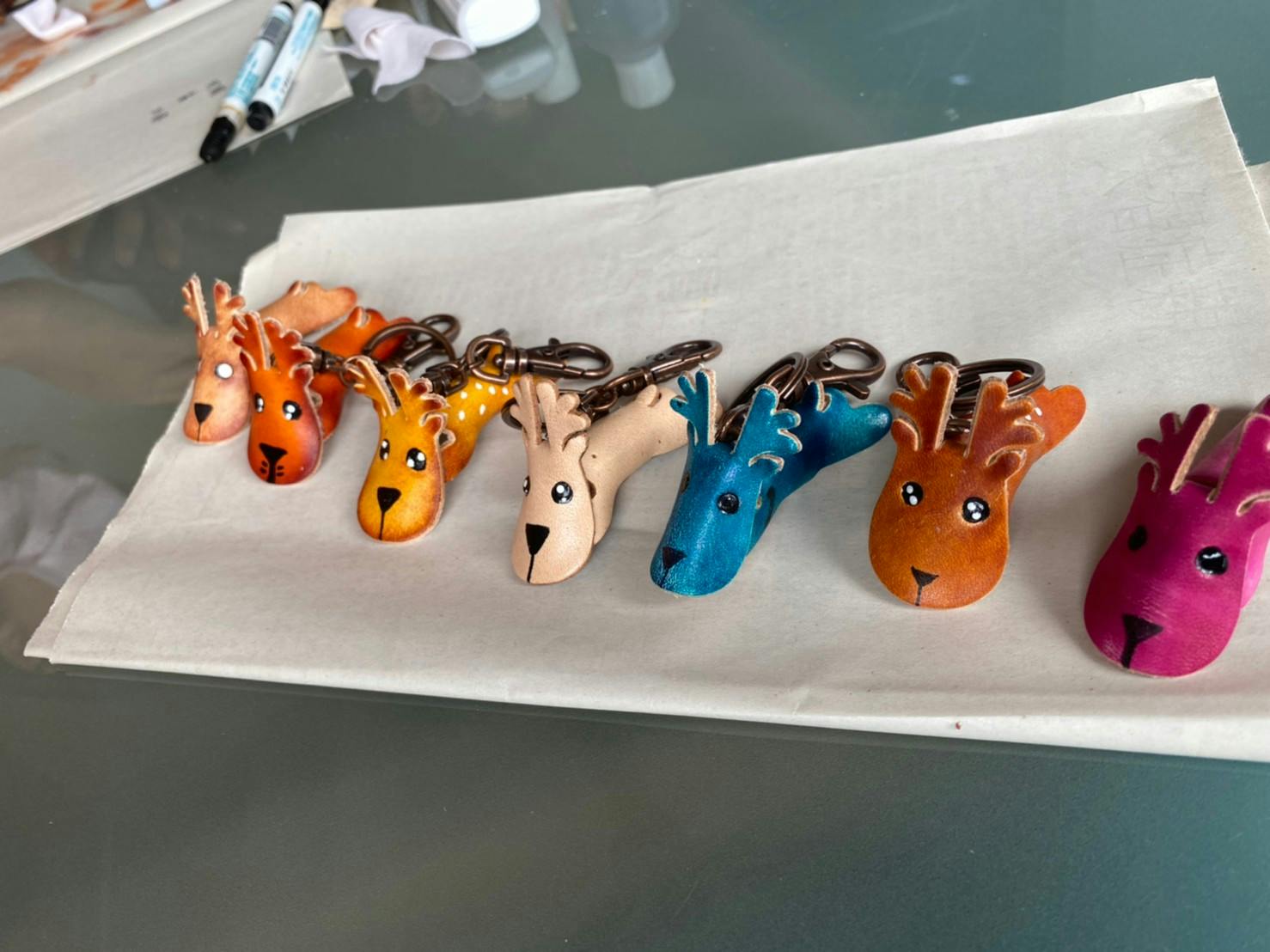 Colorful deer-shaped keychains arranged on a sheet of paper on a table.