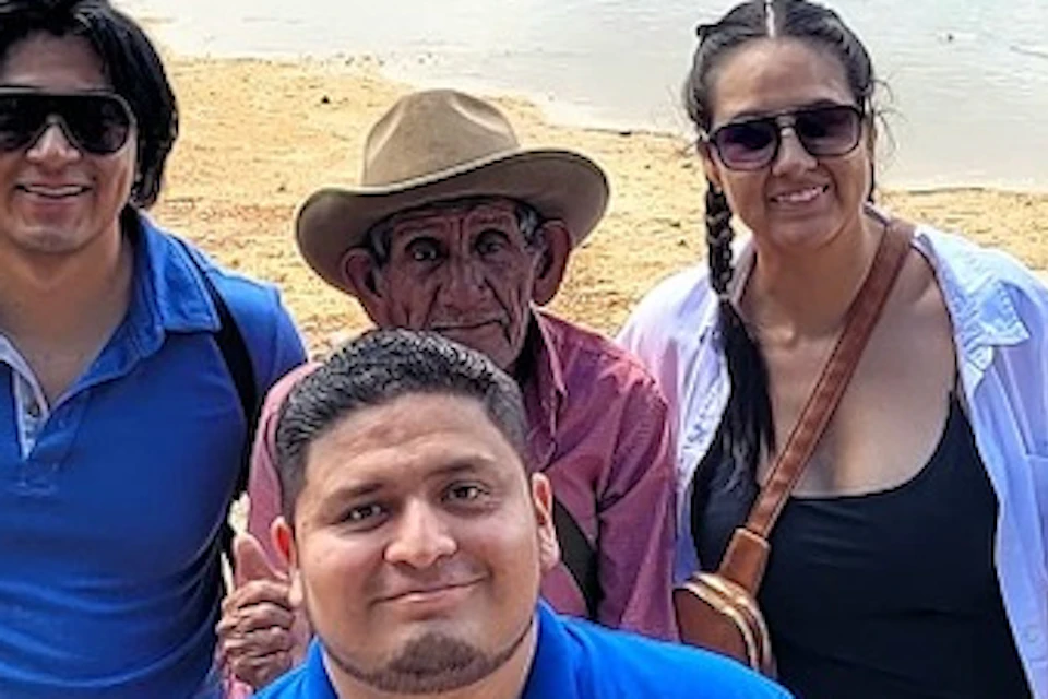 A group of people posing for a photo outdoors with a scenic mountainous landscape in the background.