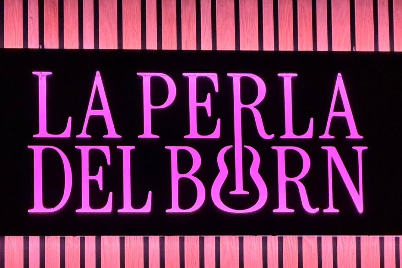粉红色霓虹灯文字“La Perla del Born” ，黑色背景，竖条纹木质镶板。
