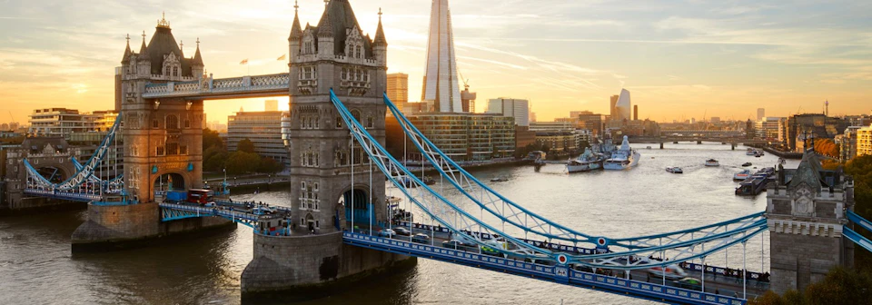 Tower Bridge in London with a view of the Shard and the Thames River at sunset.