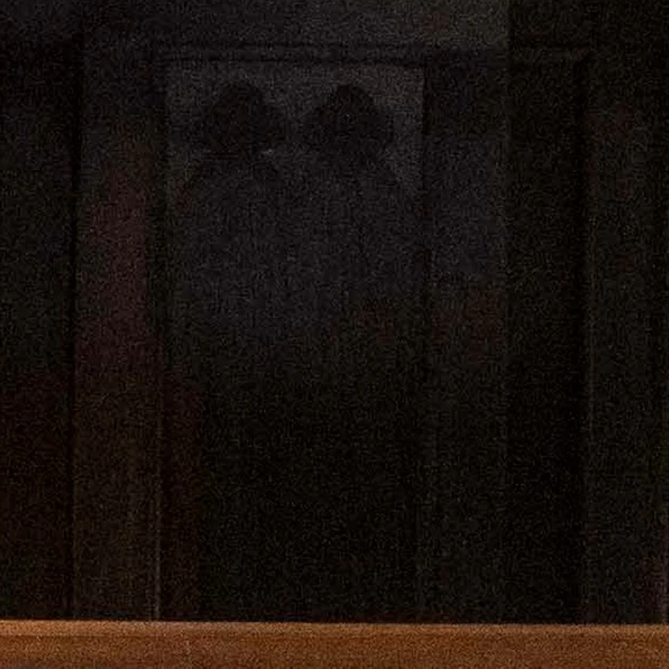 People sitting around a large interactive table in a dimly lit room with wooden beams and green patterned walls, wearing headphones.